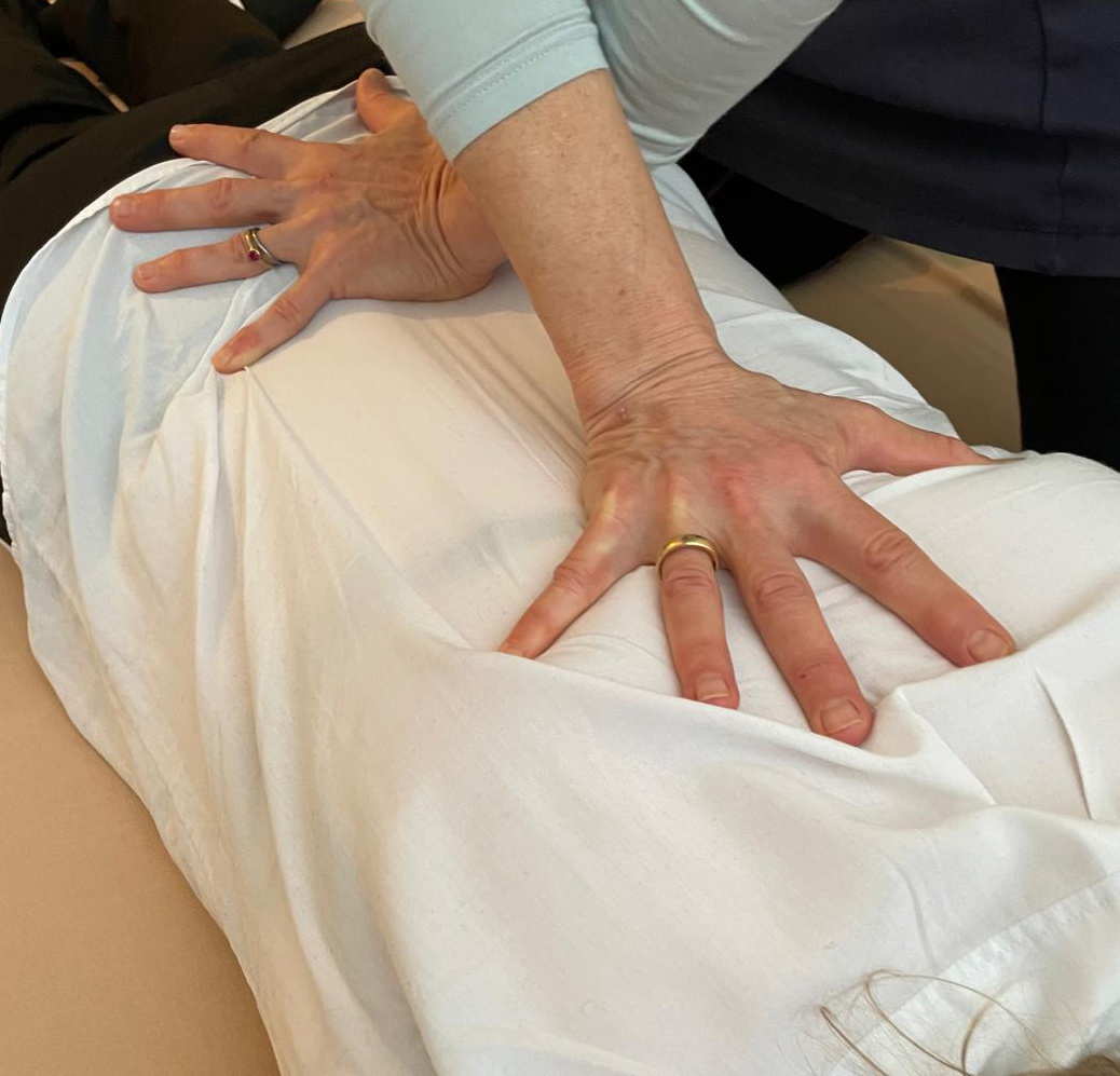 Ornits Hände üben sanften Druck während einer Shiatsu-Behandlung aus